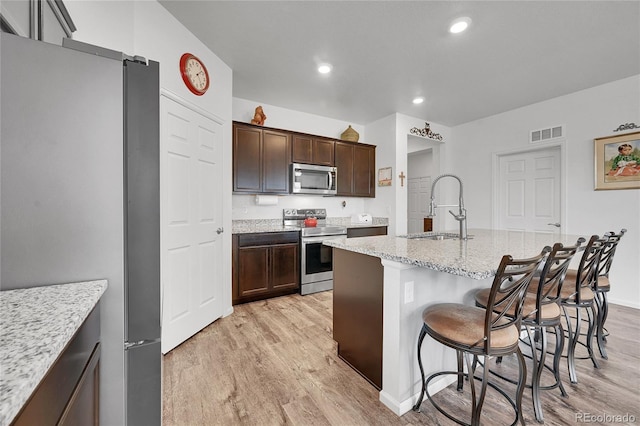 kitchen featuring a sink, appliances with stainless steel finishes, light wood finished floors, and visible vents