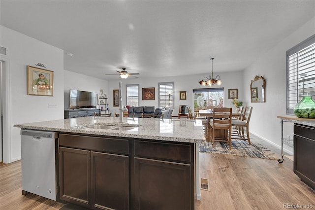 kitchen with dark brown cabinets, light wood finished floors, open floor plan, a healthy amount of sunlight, and stainless steel dishwasher