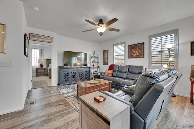 living area with plenty of natural light, ceiling fan, light wood finished floors, and visible vents