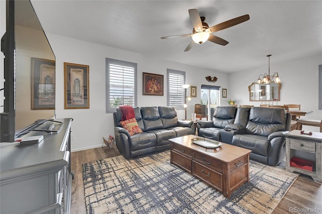 living room with ceiling fan with notable chandelier and dark wood-type flooring