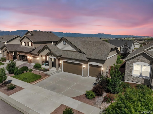 3326 Daydreamer Dr, Colorado Springs, CO 80908 - view of front of home featuring an attached garage, driveway, stone siding, roof with shingles, and a mountain view