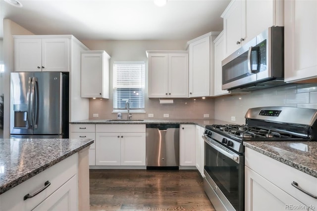 3326 Daydreamer Dr, Colorado Springs, CO 80908 - kitchen with stainless steel appliances, dark wood-style flooring, white cabinetry, dark stone countertops, and decorative backsplash