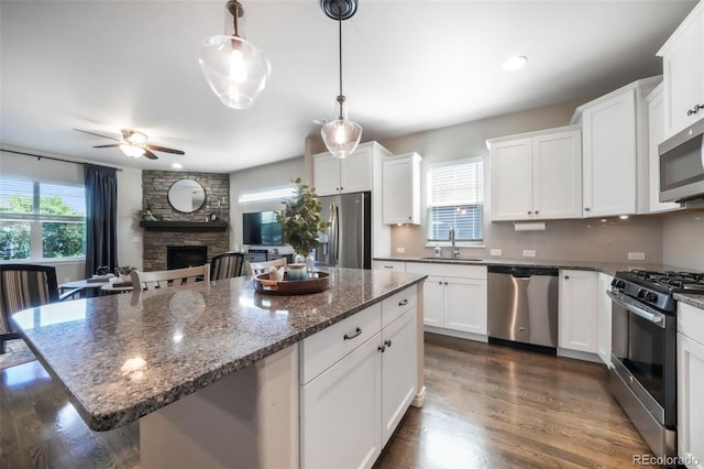 3326 Daydreamer Dr, Colorado Springs, CO 80908 - kitchen featuring appliances with stainless steel finishes, white cabinetry, a ceiling fan, and a fireplace