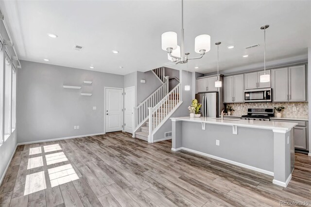 3429 Hardin St, Castle Rock, CO 80109 - kitchen with stainless steel appliances, gray cabinetry, decorative backsplash, a center island with sink, and light countertops