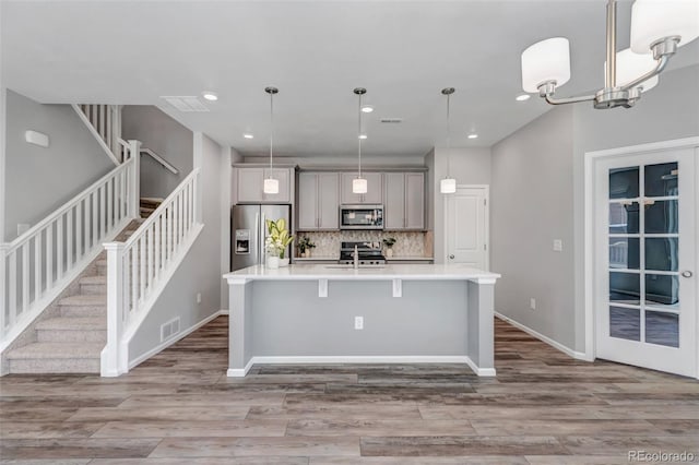 3429 Hardin St, Castle Rock, CO 80109 - kitchen with stainless steel appliances, an island with sink, light countertops, wood finished floors, and tasteful backsplash