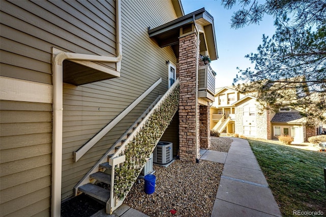 view of side of home with central AC and a yard