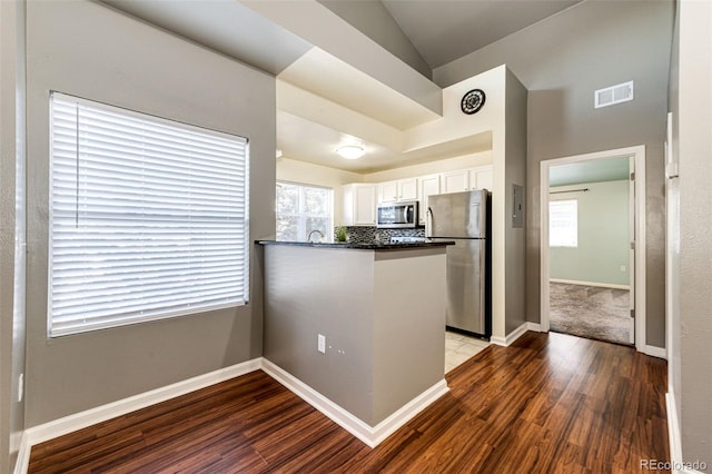 kitchen with kitchen peninsula, appliances with stainless steel finishes, white cabinetry, and plenty of natural light