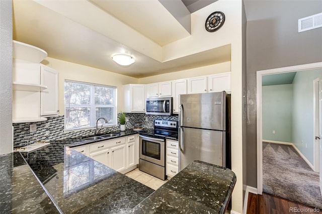 kitchen featuring appliances with stainless steel finishes, light wood-type flooring, tasteful backsplash, sink, and white cabinetry