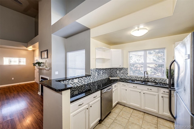 kitchen featuring white cabinetry, sink, stainless steel appliances, light hardwood / wood-style flooring, and kitchen peninsula