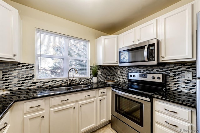 kitchen featuring dark stone countertops, sink, white cabinetry, and stainless steel appliances