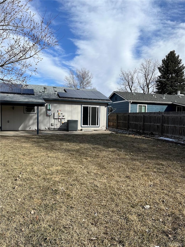 rear view of house featuring solar panels, a lawn, and central AC