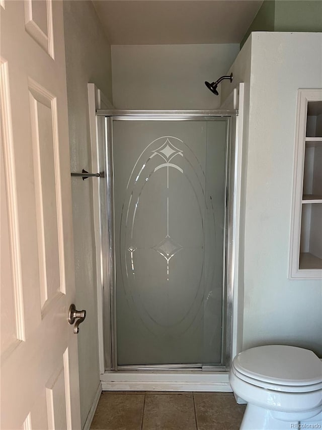 bathroom featuring tile flooring, toilet, and a shower with door