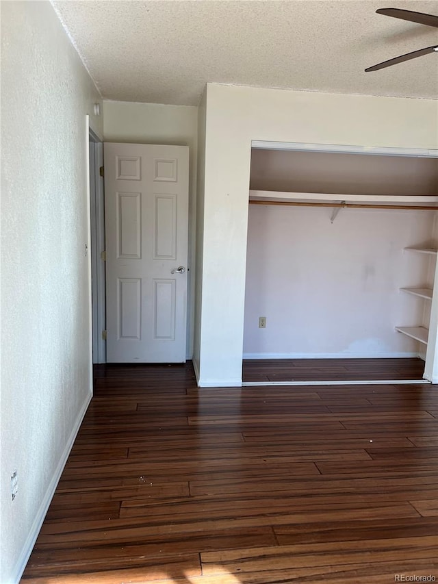 unfurnished bedroom featuring ceiling fan, a textured ceiling, and dark wood-type flooring