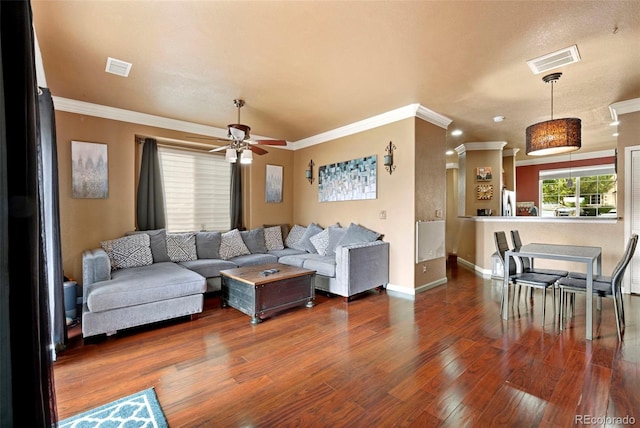living room featuring a ceiling fan, baseboards, visible vents, crown molding, and wood finished floors