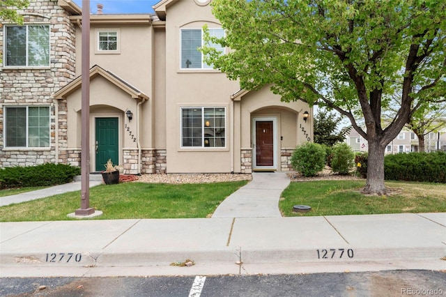 view of front facade featuring stone siding, stucco siding, and a front lawn