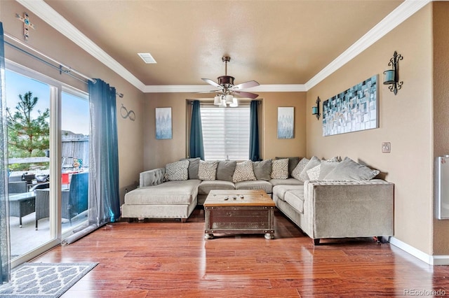 living area featuring a ceiling fan, crown molding, plenty of natural light, and wood finished floors