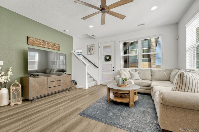 living room featuring a textured ceiling, light hardwood / wood-style floors, and ceiling fan