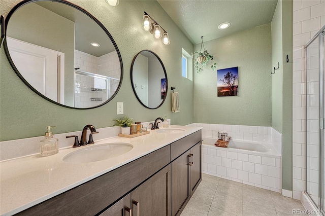 bathroom with tile patterned flooring, plus walk in shower, vanity, and a textured ceiling