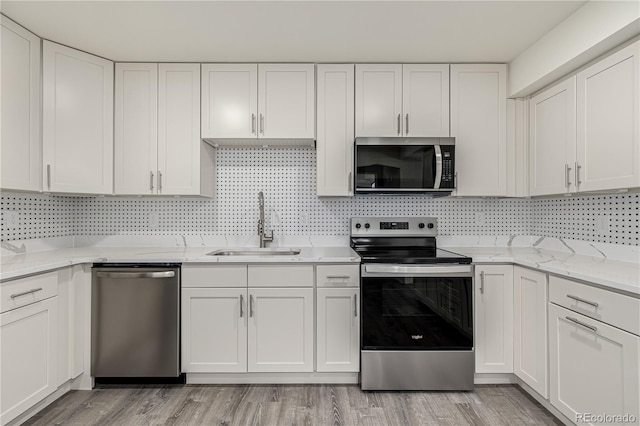 kitchen with tasteful backsplash, sink, white cabinets, and appliances with stainless steel finishes