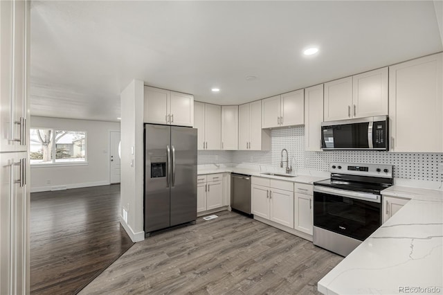 kitchen featuring light stone counters, hardwood / wood-style flooring, stainless steel appliances, and white cabinets