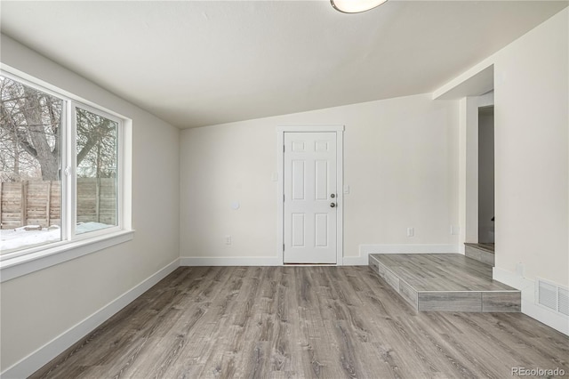 spare room featuring lofted ceiling and light hardwood / wood-style flooring