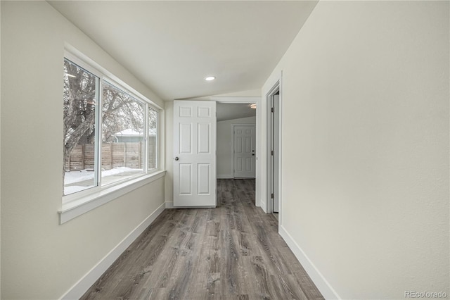 hall featuring hardwood / wood-style flooring and vaulted ceiling