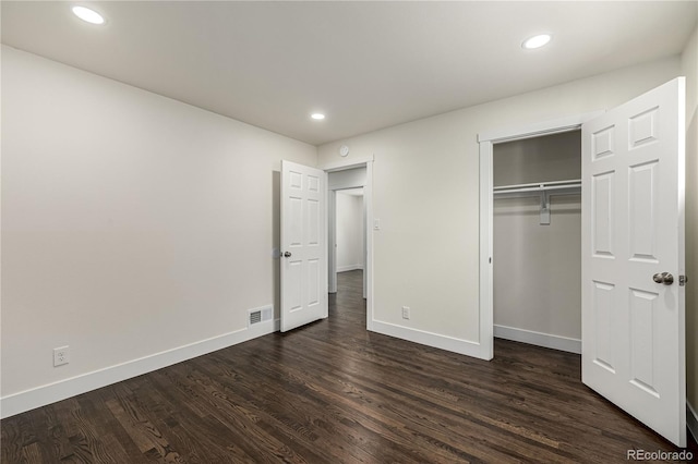 unfurnished bedroom with dark hardwood / wood-style flooring and a closet