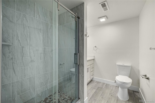 bathroom featuring vanity, a shower with door, and toilet