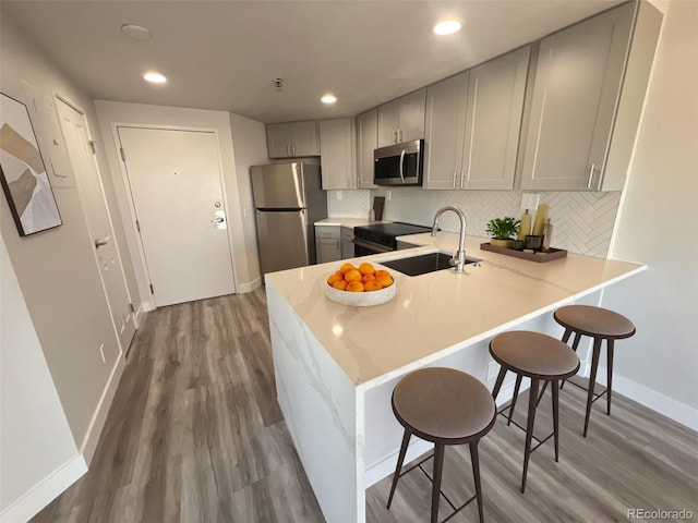 kitchen with appliances with stainless steel finishes, light countertops, a sink, and gray cabinetry