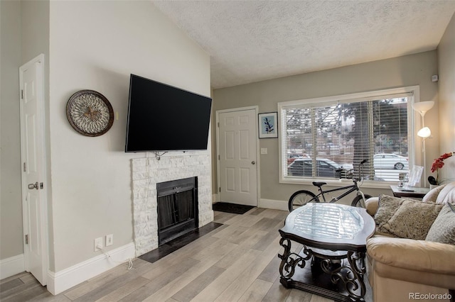 living room featuring a fireplace, a textured ceiling, and light wood-type flooring