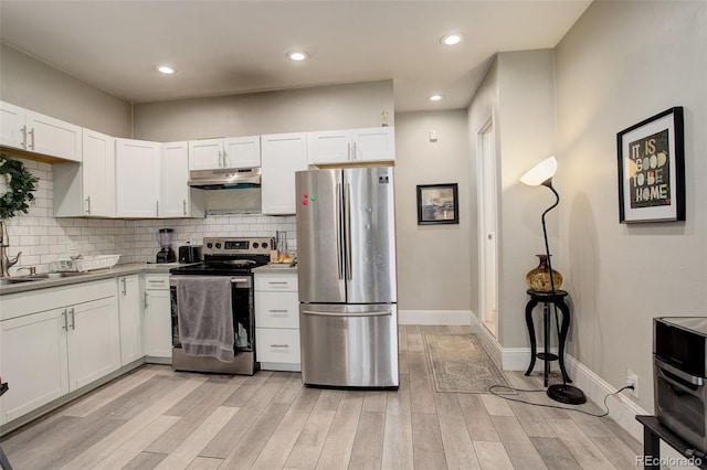 kitchen with appliances with stainless steel finishes, tasteful backsplash, white cabinetry, sink, and light wood-type flooring