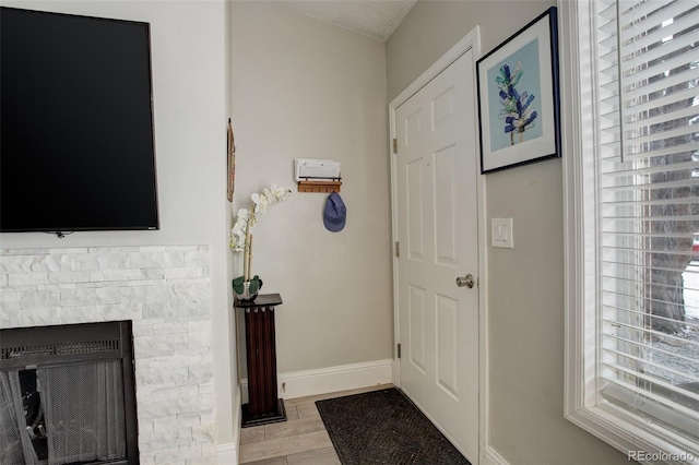 foyer featuring a stone fireplace and light wood-type flooring