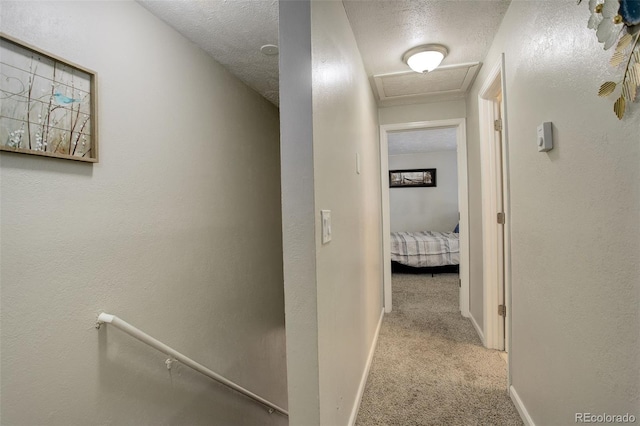 corridor featuring light colored carpet and a textured ceiling