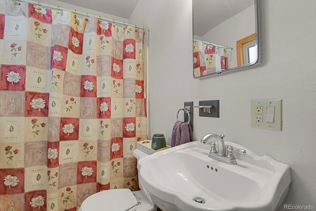 bathroom featuring sink, curtained shower, and toilet