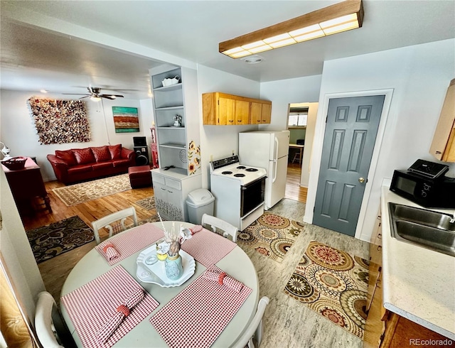 kitchen featuring white appliances, light wood-style flooring, ceiling fan, light countertops, and a sink