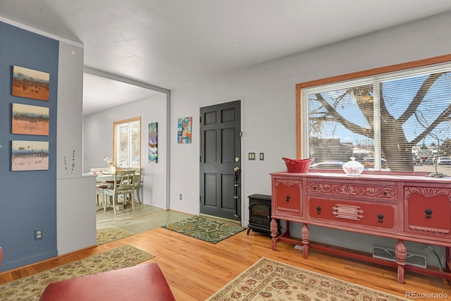 foyer entrance with visible vents, wood finished floors, and a wood stove