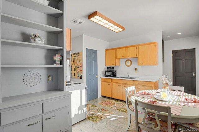 kitchen featuring visible vents, range, light countertops, light brown cabinetry, and a sink