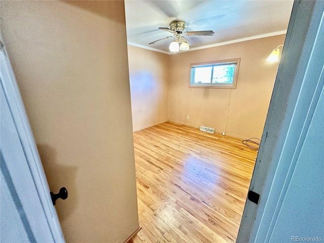 unfurnished room with ornamental molding, visible vents, ceiling fan, and wood finished floors