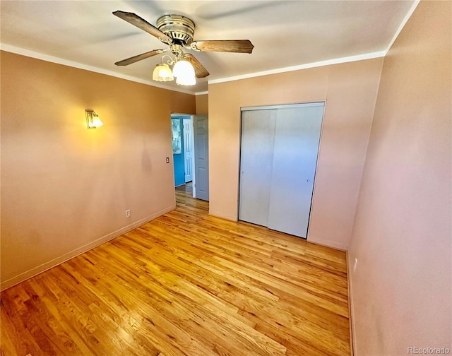 unfurnished bedroom featuring crown molding, a closet, ceiling fan, light wood-type flooring, and baseboards