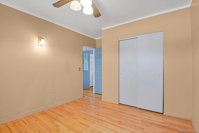 unfurnished bedroom featuring crown molding, a closet, light wood-style floors, a ceiling fan, and baseboards