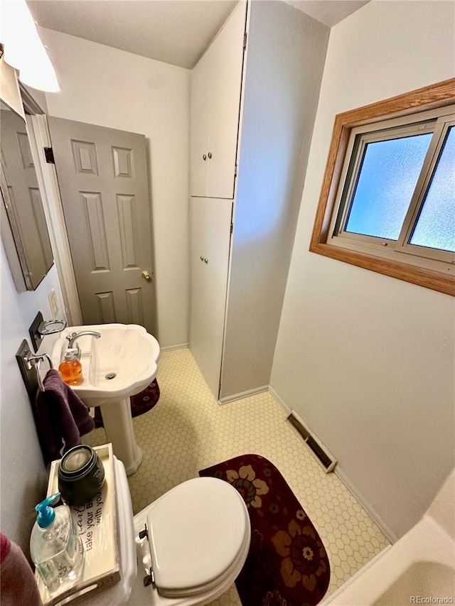 bathroom with toilet, baseboards, visible vents, and a sink