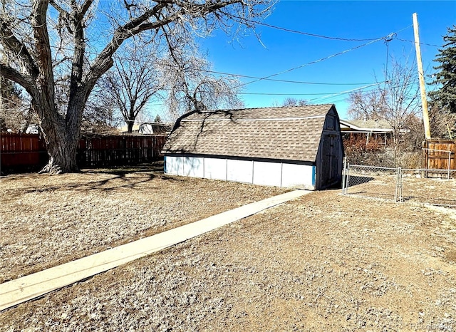 view of side of home featuring an outbuilding, a shingled roof, and fence