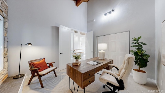 office area with a high ceiling and light colored carpet