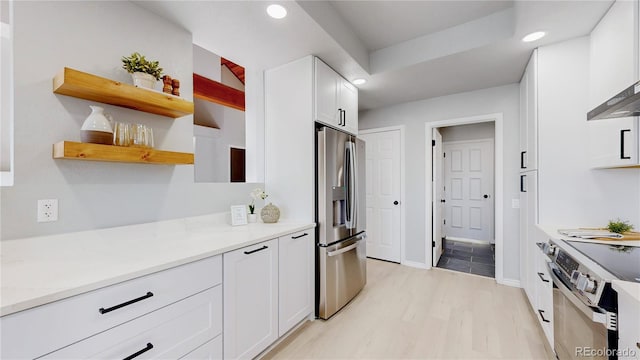 kitchen featuring appliances with stainless steel finishes, recessed lighting, white cabinetry, light wood-style floors, and light stone countertops