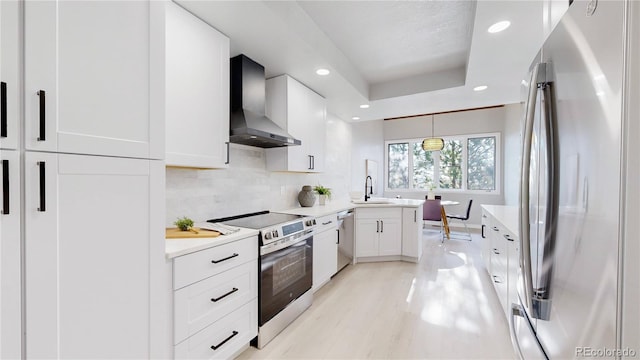 kitchen featuring appliances with stainless steel finishes, wall chimney range hood, white cabinets, recessed lighting, and light countertops