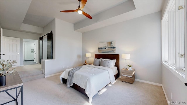 carpeted bedroom with a barn door, baseboards, and ceiling fan