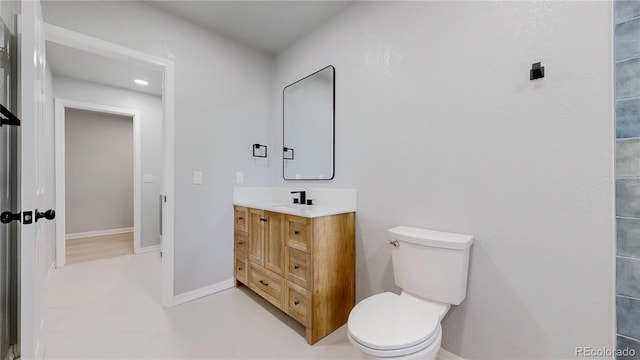 bathroom with toilet, vanity, and baseboards