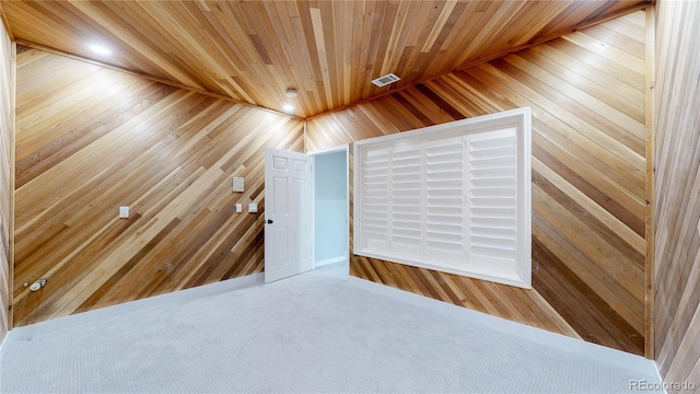 carpeted spare room with wood ceiling and wooden walls
