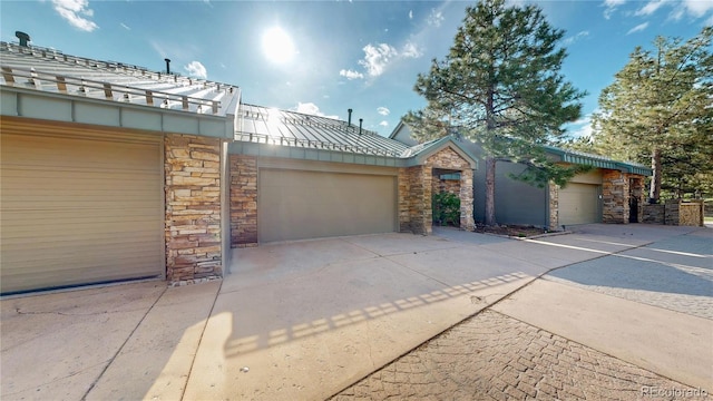 view of front of property featuring stone siding, driveway, and an attached garage