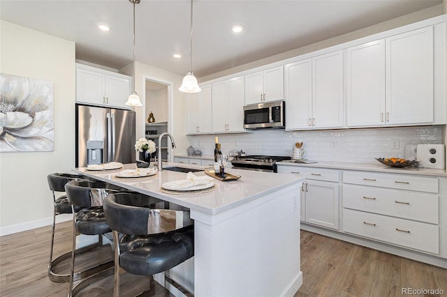1953 Morgan Dr, Erie, CO 80516 - kitchen featuring stainless steel appliances, a sink, a breakfast bar, tasteful backsplash, and recessed lighting